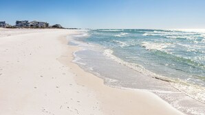 A beach with a clear sky and ocean waves. There are buildings in the background. - Gulf/Beachfront Condo | Private Beach (Santa Rosa Beach)