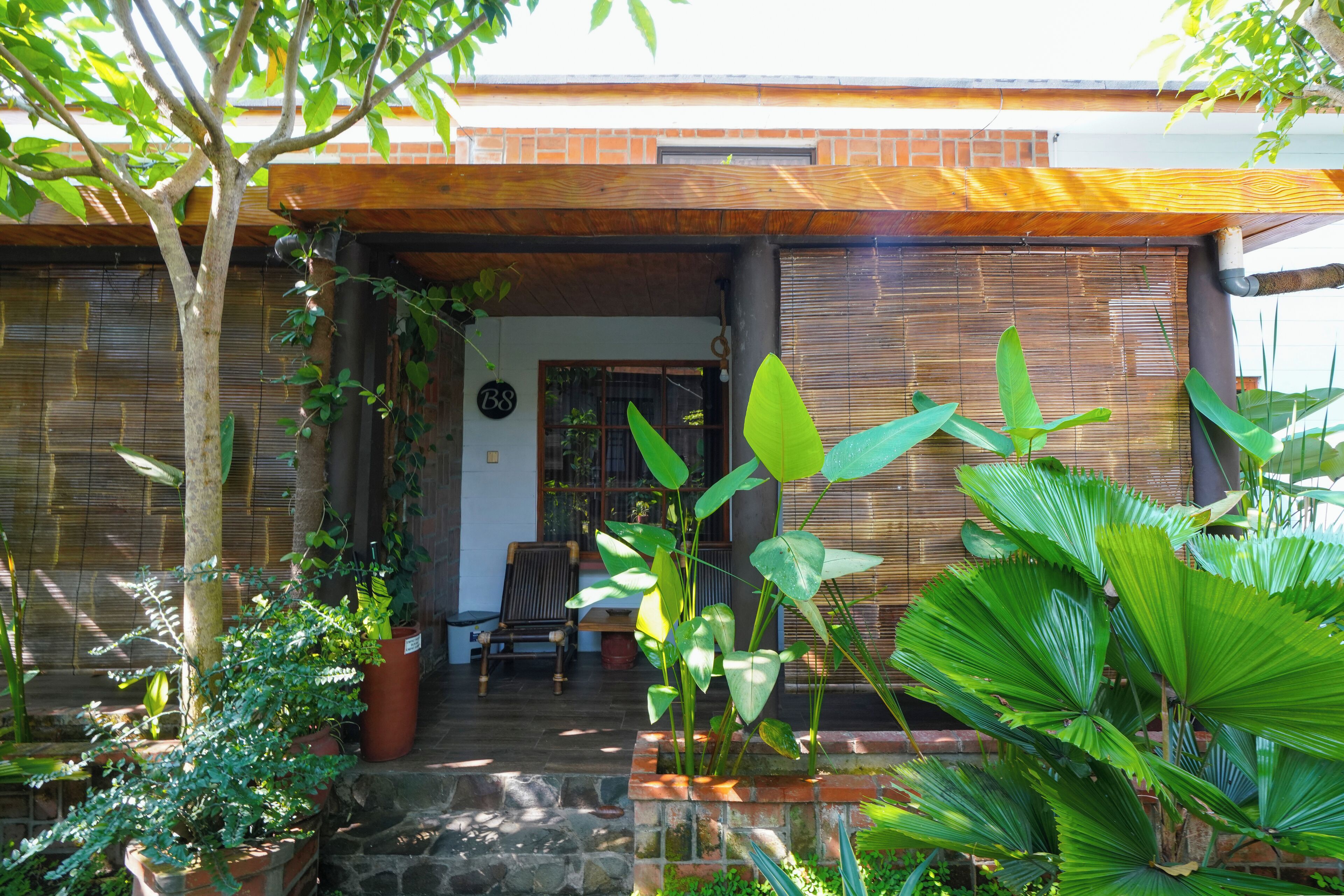 A house with a covered porch, stone steps, and various potted plants.