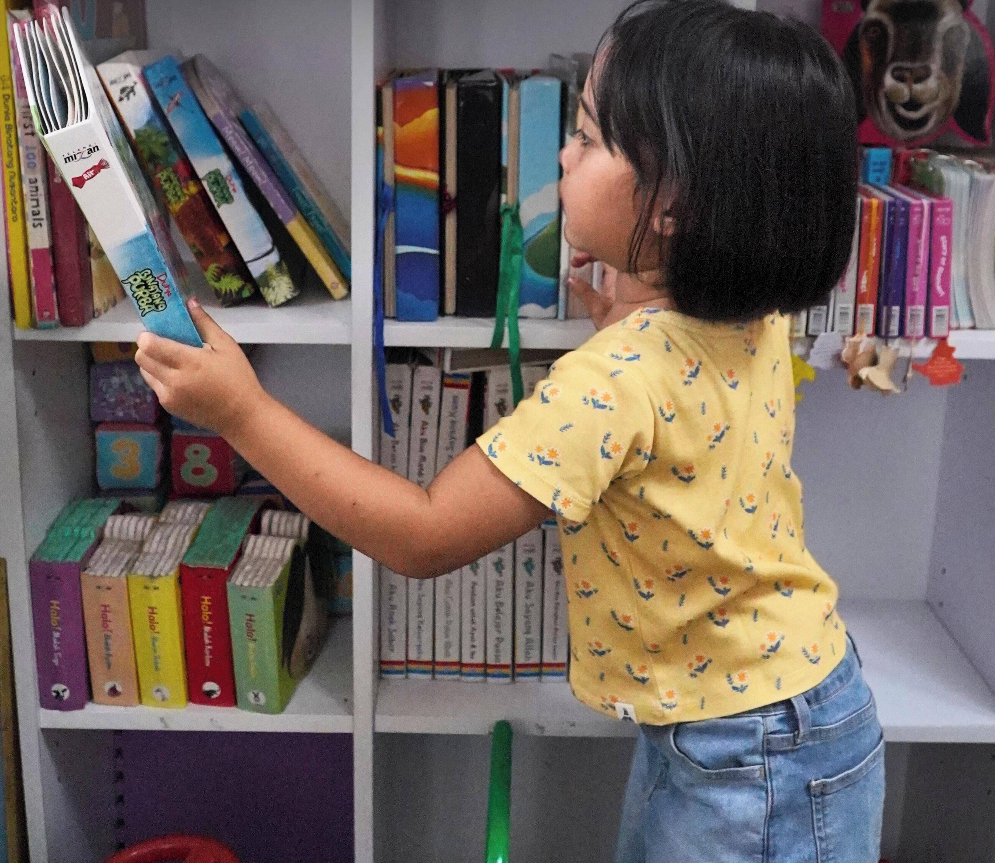 A child pointing at a bookshelf filled with books.