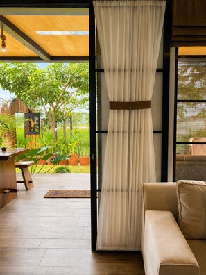 An open doorway leading to a garden with a wooden bench and potted plants.