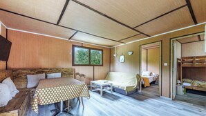 Habitación pequeña con cama, una mesita y un sofá. Una ventana proporciona luz natural y vistas a zonas verdes.