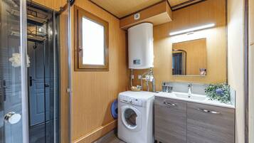 Ein kleines Badezimmer mit Waschmaschine, Toilette und Duschbereich.