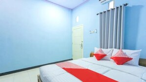 Une chambre à coucher avec un lit, un plaid rouge et deux coussins rouges.