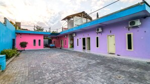 Une cour bordée de bâtiments aux couleurs vives, dotée de climatiseurs et dont le sol est pavé.
