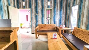 Une pièce avec un papier peint à rayures, un canapé en bois, une table en bois et un téléviseur.