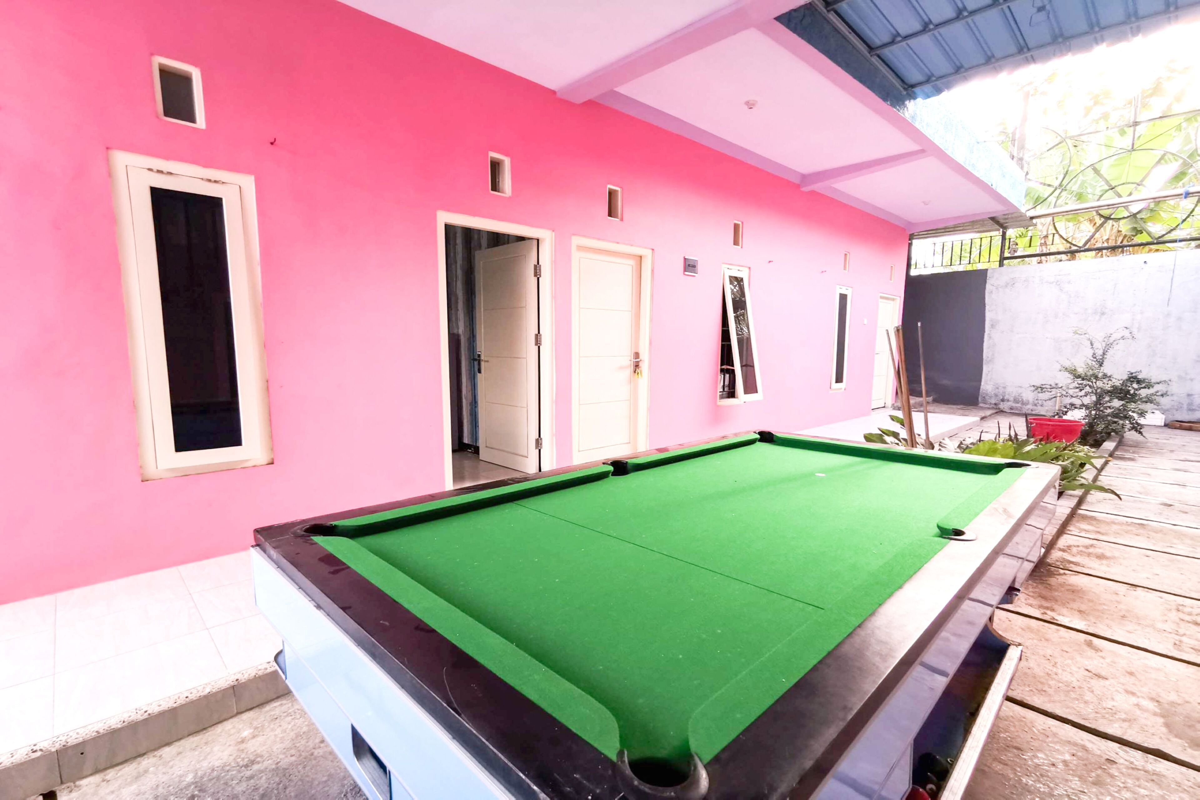 A pool table in a room with pink walls and a tiled floor.