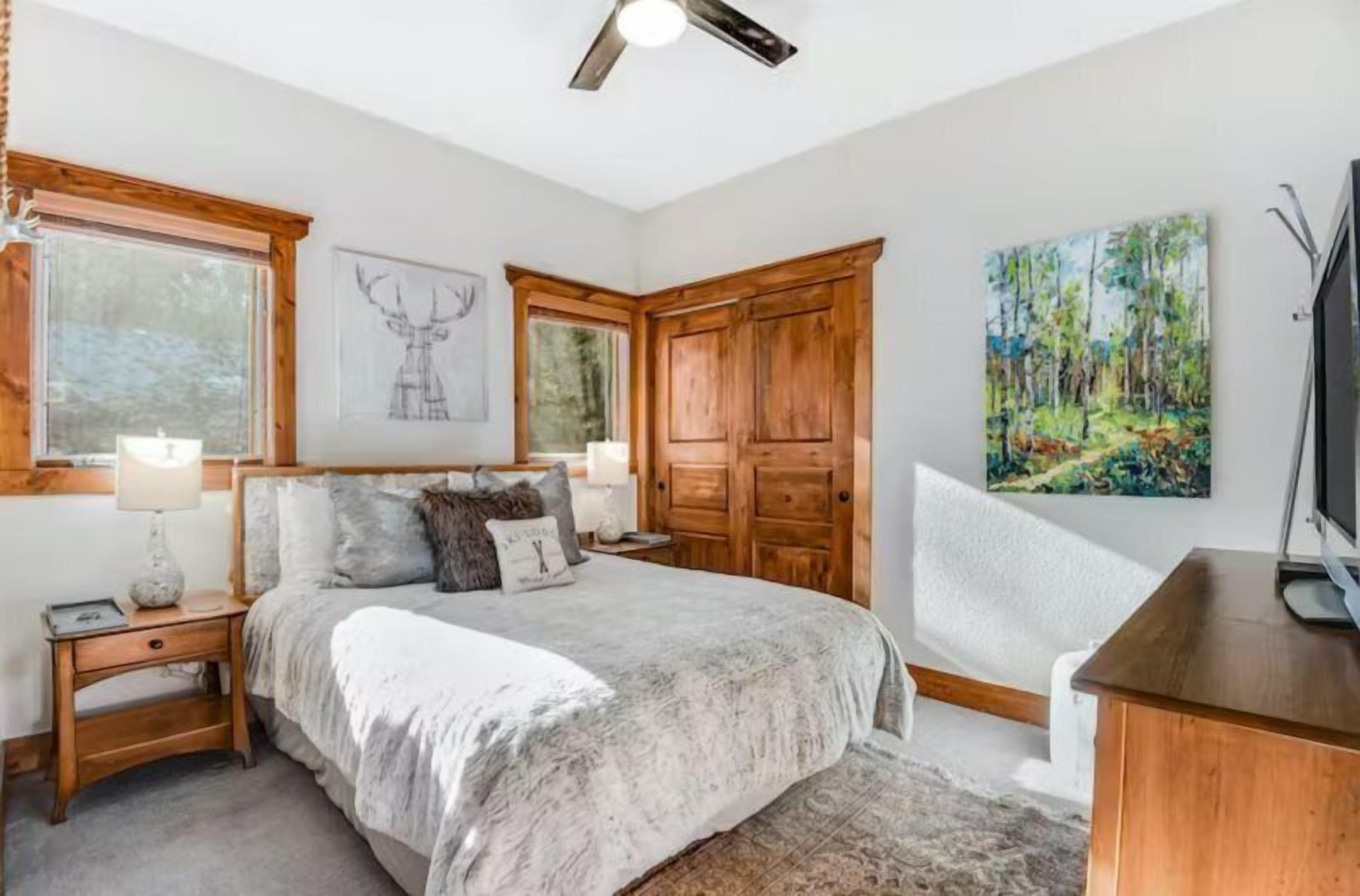 Een slaapkamer met een bed, een houten garderobe, een bureau en een schilderij.