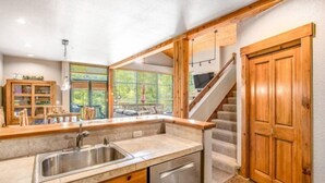 A kitchen with a built-in sink, wooden cabinets, and a view to the outdoor seating area. - Lovely Townhome a Half-mile From Keystone Gondola W/shared Hot-tub & Excellent Views (Keystone)