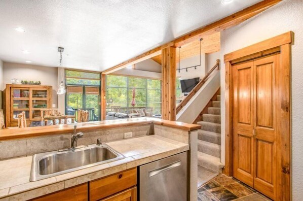 A kitchen with a built-in sink, wooden cabinets, and a view to the outdoor seating area.