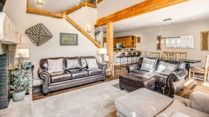 A spacious living area with a large leather sofa, a fireplace, and a kitchen in the background. - Lovely Townhome a Half-mile From Keystone Gondola W/shared Hot-tub & Excellent Views (Keystone)