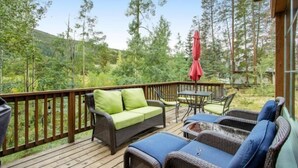 A wooden deck with wicker furniture, a red umbrella, and a view of a forested area. - Lovely Townhome a Half-mile From Keystone Gondola W/shared Hot-tub & Excellent Views (Keystone)