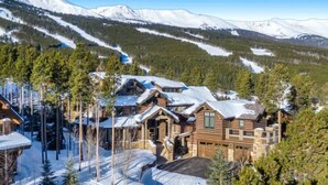 Un resort in stile baita di legno con diversi edifici, circondato da montagne innevate e pini.