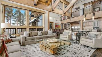 A spacious living area with a high ceiling, large windows, and a modern fireplace.