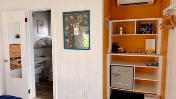 A room with a bed, a wardrobe, a shelf with items, and a door leading to another room.