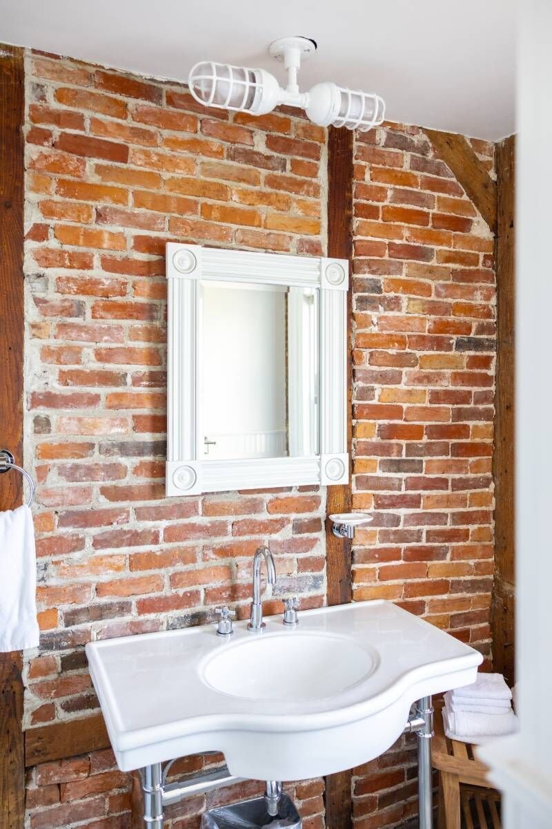 Casa de banho com lavatório branco, espelho e candeeiro de teto branco.