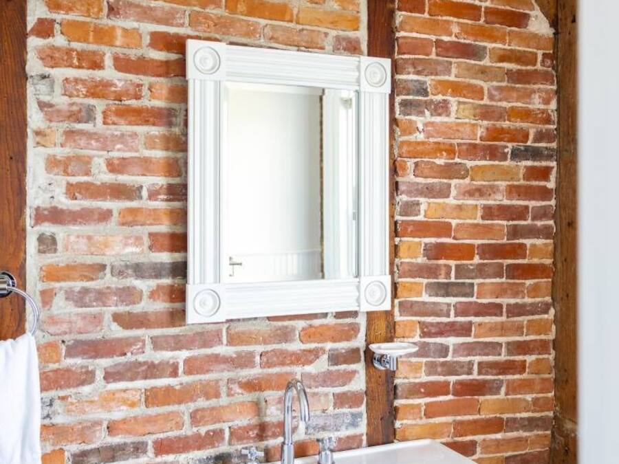 Casa de banho com lavatório branco, espelho e candeeiro de teto branco.