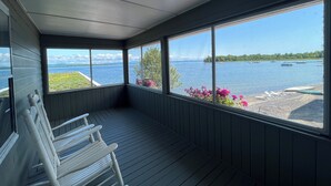 A room with a view of a lake, wooden benches, and a window with a view of boats. - The North Hero House Inn & Restaurant (North Hero)