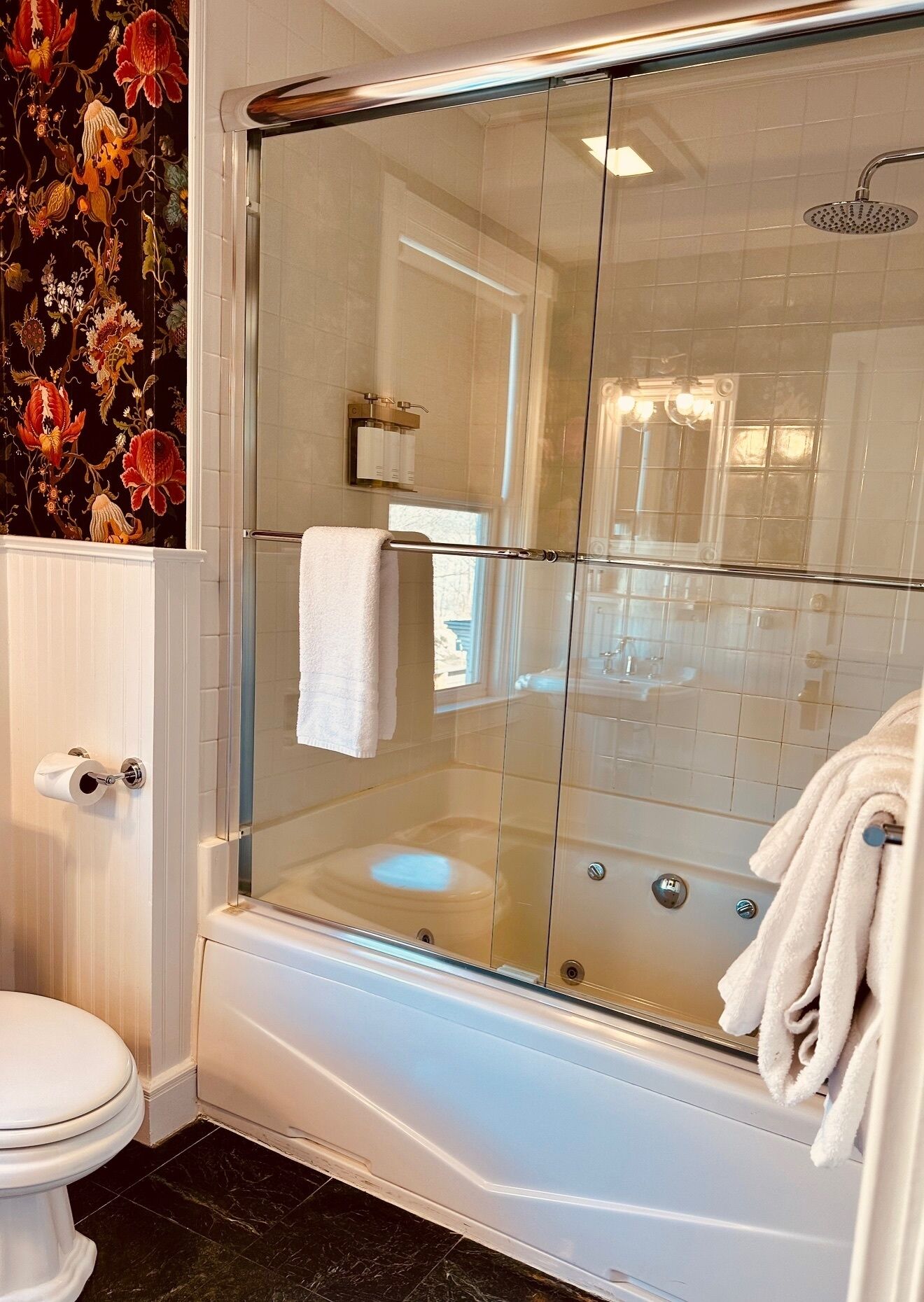 Een douchecabine met glazen wanden, een wit toilet en een handdoekhouder.