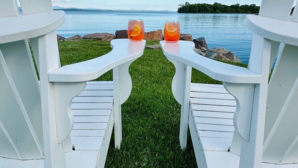 Two white Adirondack chairs facing a body of water with a clear sky. - The North Hero House Inn & Restaurant (North Hero)