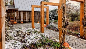 A rustic outdoor area with a wooden pergola, a sign for 'North Hero House Inn & Restaurant', and a garden with flowers and pumpkins. - The North Hero House Inn & Restaurant (North Hero)