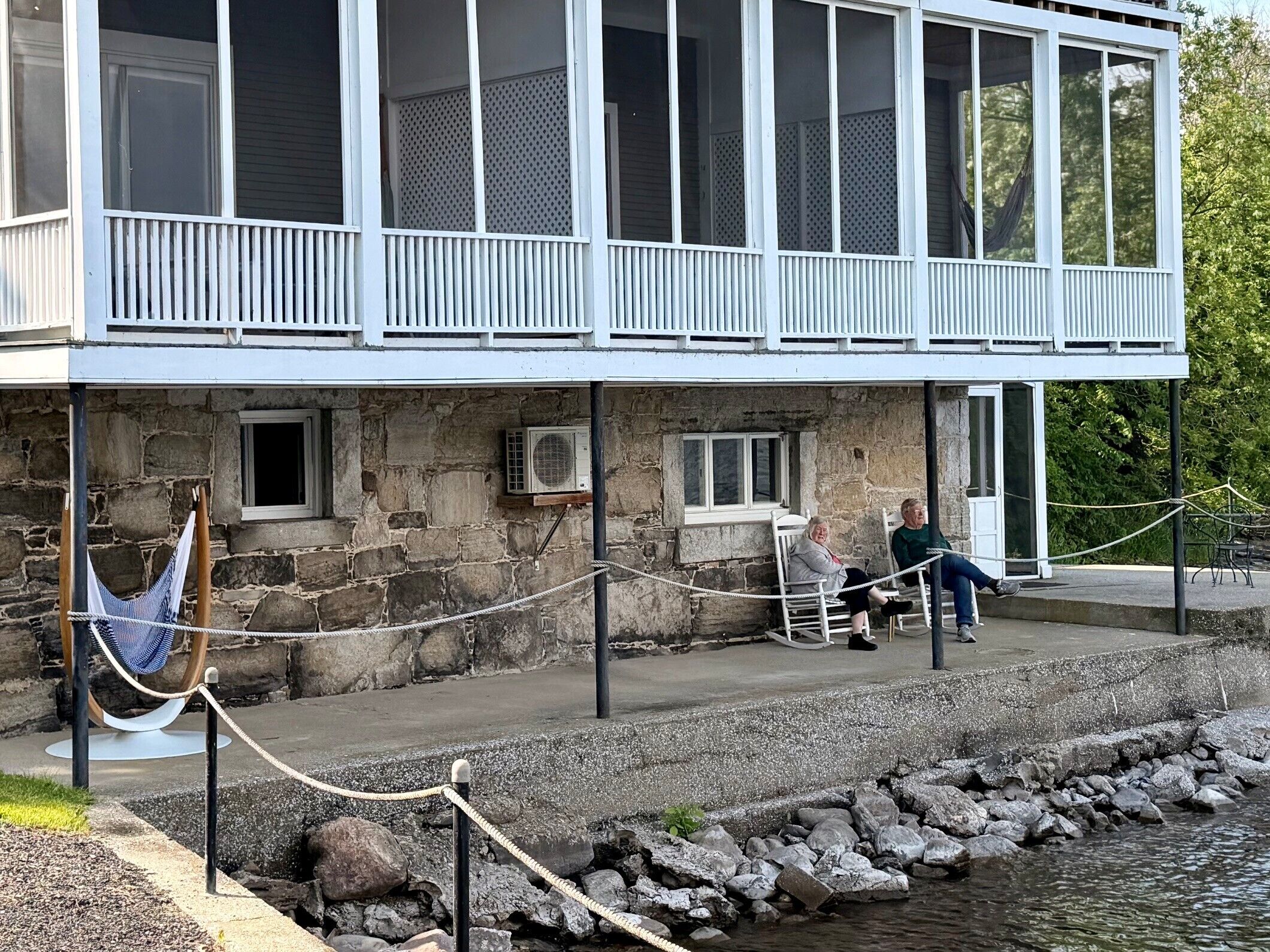 A building with a stone facade, a balcony with white railings, and a rope barrier.