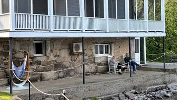 A building with a stone facade, a balcony with white railings, and a rope barrier.