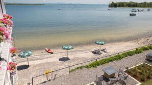 A lakeside view with a sandy beach, kayaks, and umbrellas. - The North Hero House Inn & Restaurant (North Hero)