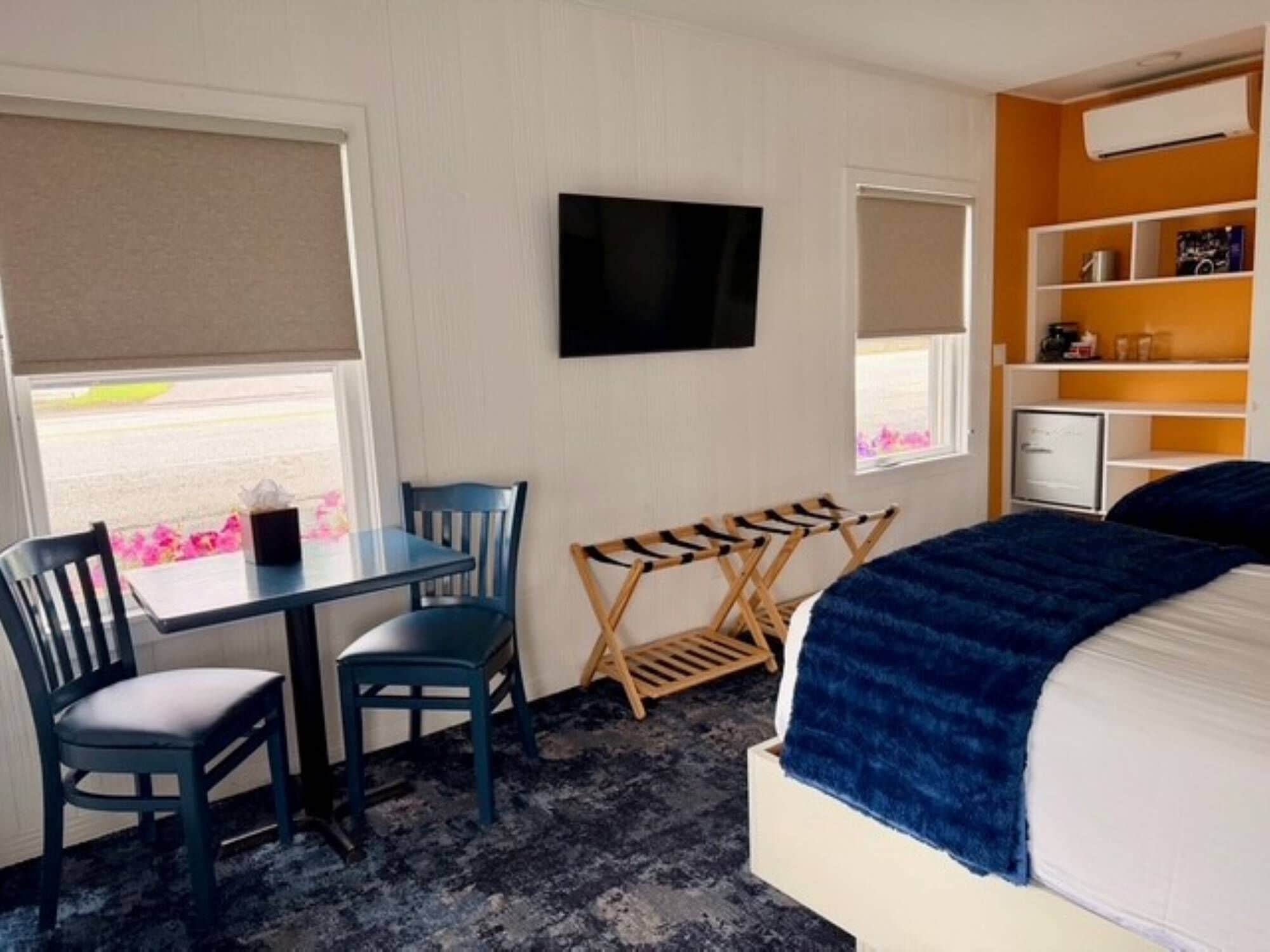 A room with a bed, a desk, two chairs, a television, and a window with a view.