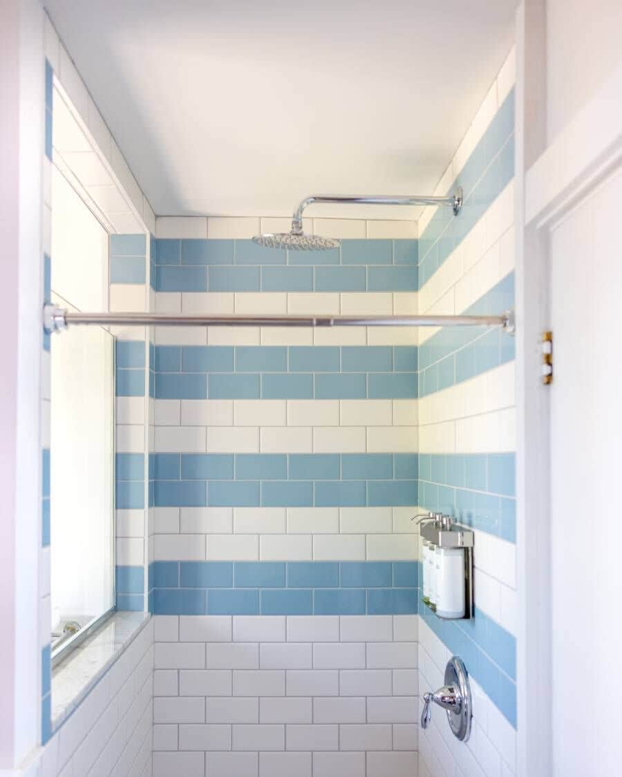 Un baño con baldosas azules y blancas, una ducha con puerta de vidrio y un perchero para toallas.