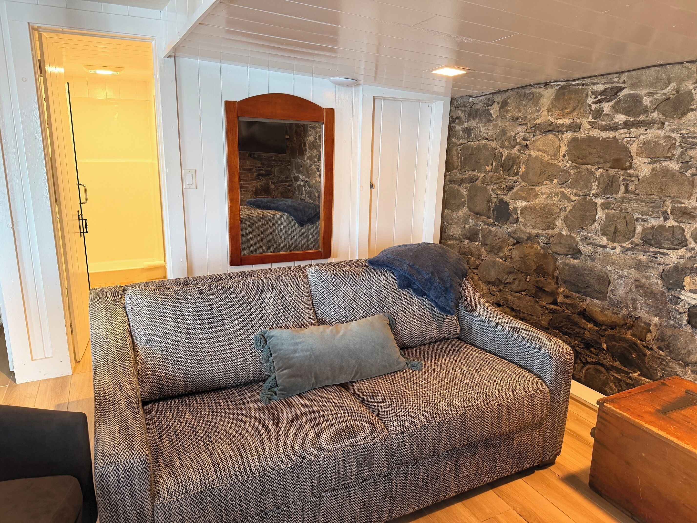 Una habitación acogedora con un sofá estampado, una pared de piedra y una puerta de madera.