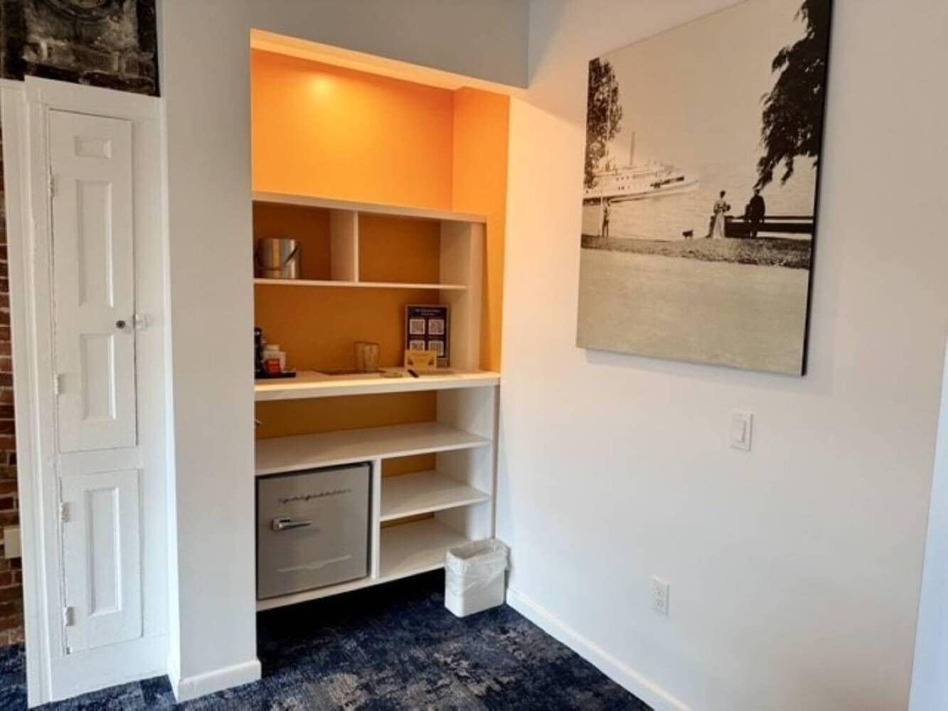 A room with a built-in shelving unit, a door, and a framed picture on the wall.
