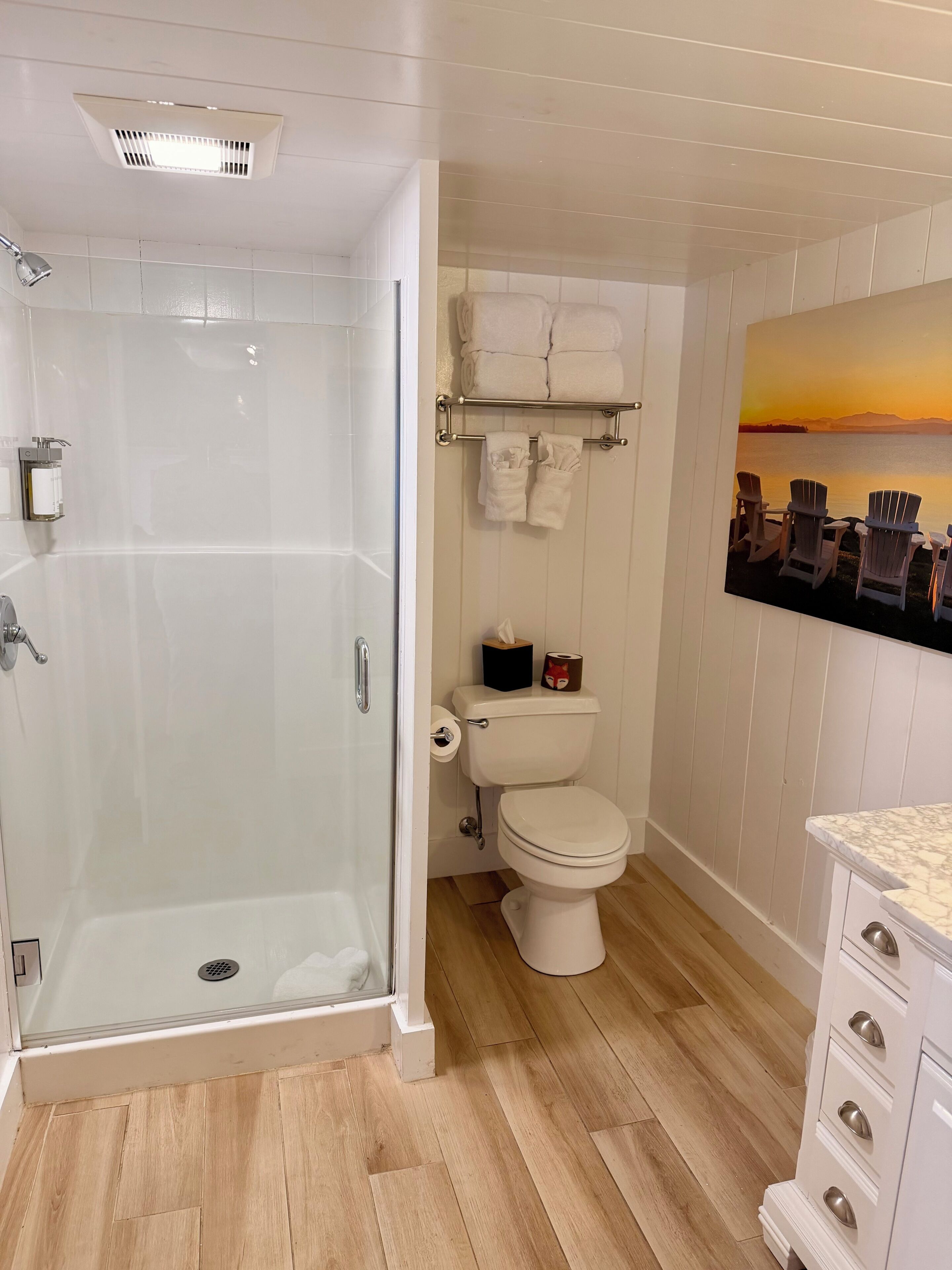 A bathroom with a glass-enclosed shower, a toilet, and a sink with a marble countertop.