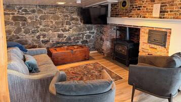 Ein gemütliches Wohnzimmer mit Steinwand, Kamin, Fernseher und bequemen Sitzgelegenheiten.