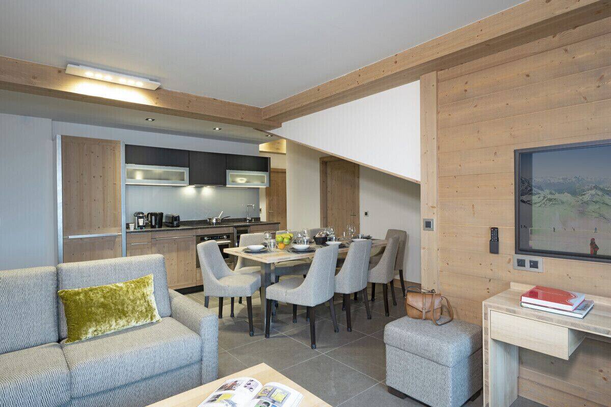 A modern living room with a sofa, a coffee table, and a dining area with chairs and a table.