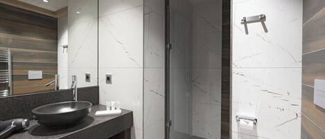 A modern bathroom with a large mirror, a black basin, and a shower area.
