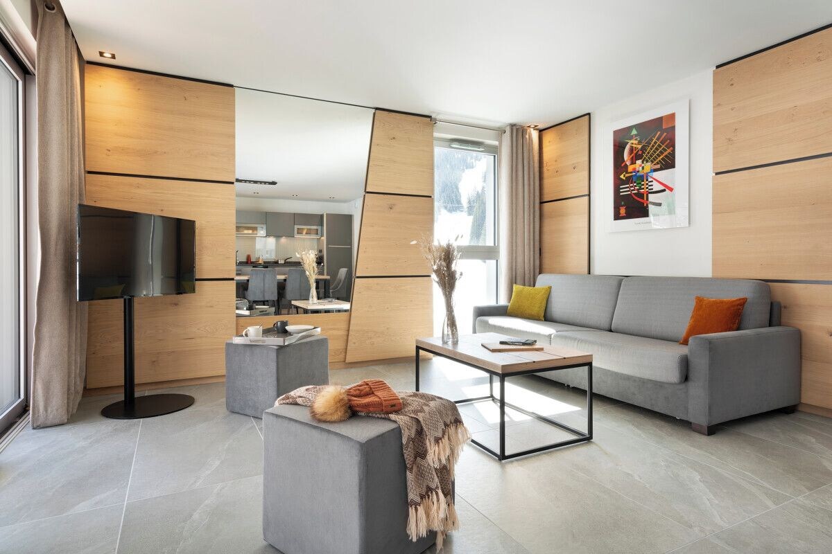 A modern living room with a grey sofa, a coffee table, and a flat-screen TV.