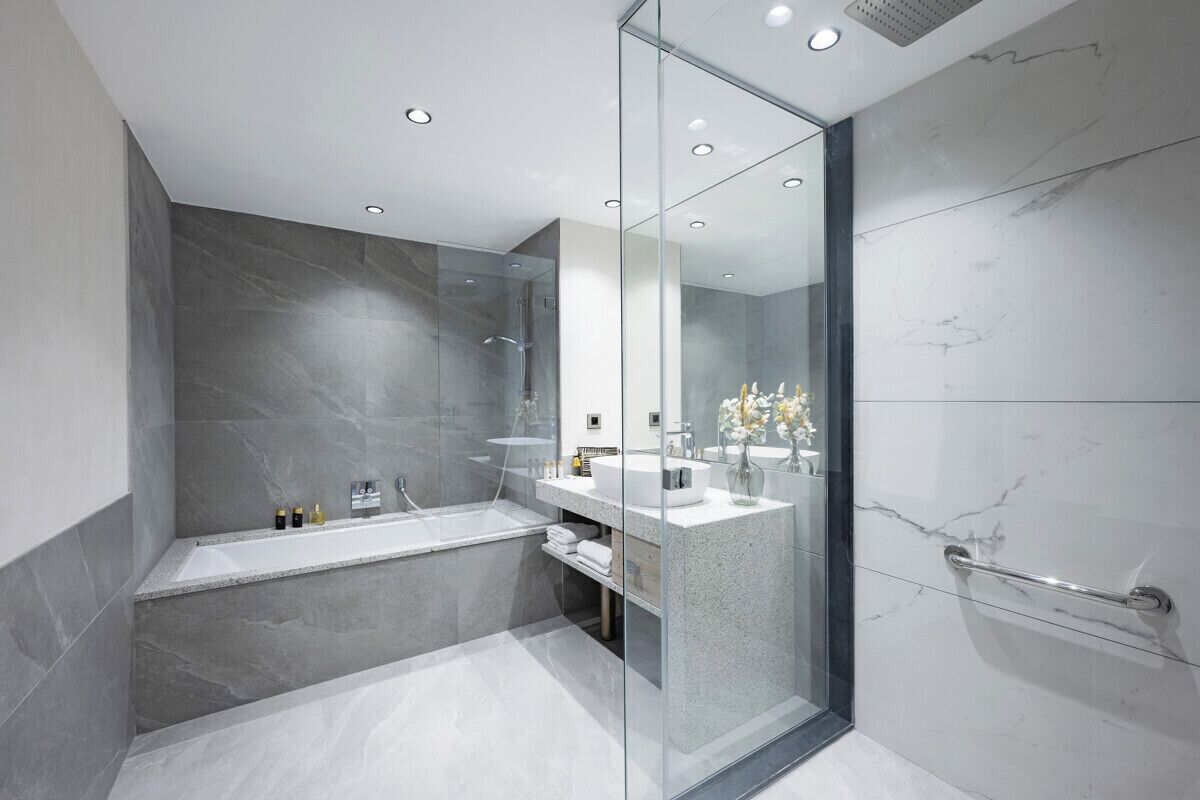 Un baño moderno con cabina de ducha de vidrio, una bañera independiente y un tocador con encimera de mármol.