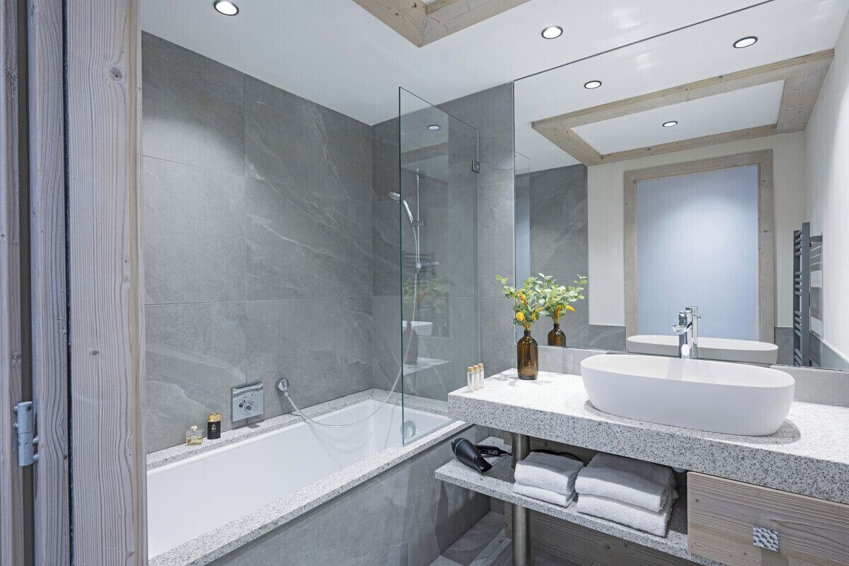 A modern bathroom with a glass-enclosed shower, a freestanding bathtub, and a large vanity with a sink and mirror.