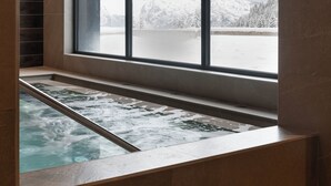 Een wellnessruimte met een groot raam met uitzicht op een besneeerd berglandschap.
