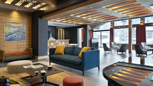 Een moderne hotel lobby met een grote bank, een bijzettafeltje en een zithoek met stoelen.