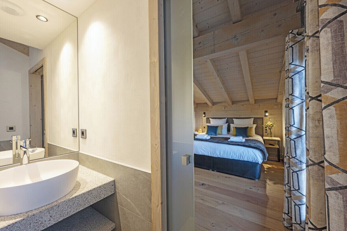 Un baño moderno con un lavamanos grande y un espejo, y un dormitorio con una cama y una mesita de noche.