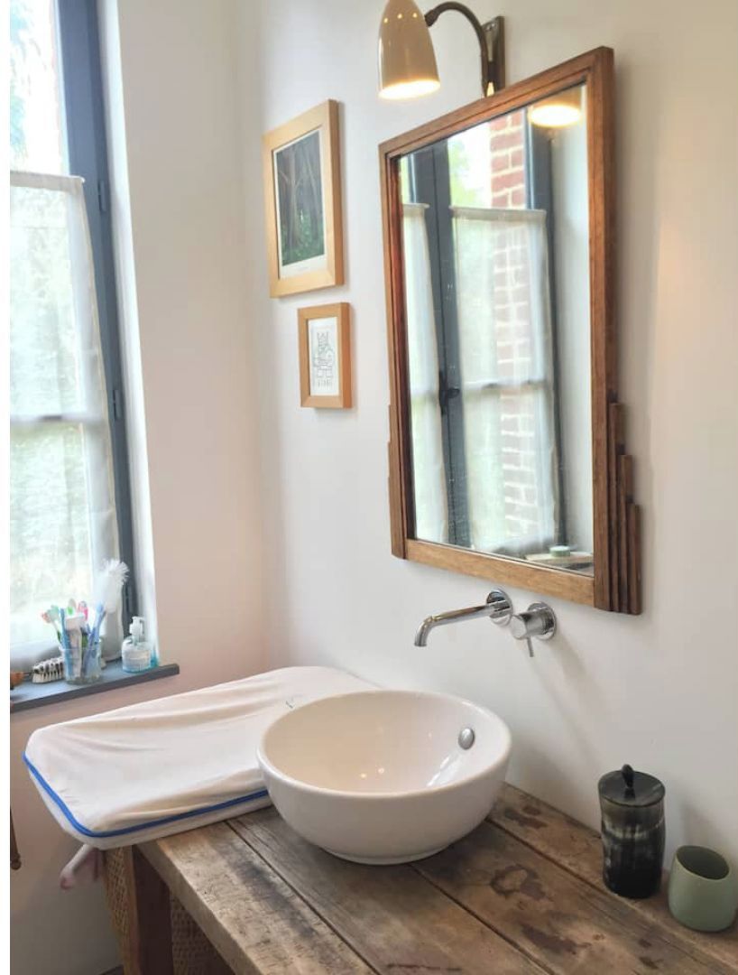 A bathroom with a white sink, a mirror, and framed pictures on the wall.