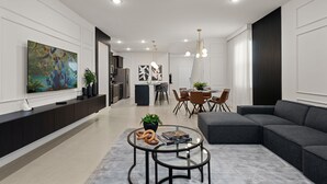 Un soggiorno moderno con un divano componibile, un tavolino in vetro e un'area pranzo con un quadro astratto in bianco e nero.