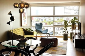 A modern living room with a large window, a sofa, a chair, a coffee table, and a TV stand. - Great location, pool, rooftop, gym, 24/7 security (Ciudad de México)