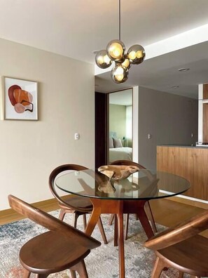 A modern dining area with a glass table and wooden chairs, a contemporary pendant light, and a framed artwork on the wall. - Great location, pool, rooftop, gym, 24/7 security (Ciudad de México)