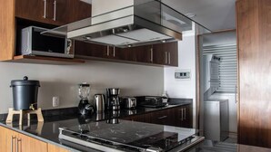 Eine moderne Küche mit dunklen Holzausziehtüren, Edelstahlgeräten und einer schwarzen Arbeitsplatte.