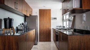 A modern kitchen with dark wood cabinets, stainless steel appliances, and a marble floor. - Great location, pool, rooftop, gym, 24/7 security (Ciudad de México)