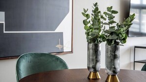 Two tall, ribbed vases with green plants on a wooden table in a room with a modern design, including a green chair and a framed abstract artwork on the wall. - Great location, pool, rooftop, gym, 24/7 security (Ciudad de México)