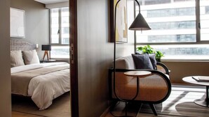 A modern hotel room with a large bed, a small round table, a chair, and a large window with a view of buildings. - In Polanco, pool, rooftop, gym, 24/7 security (Ciudad de México)