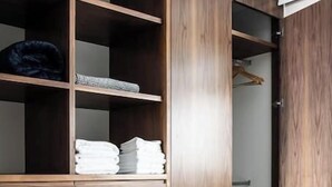 Een slaapkamer met een houten kledingkast, een bed met een zwart-wit gestreept kussen, en een radiator op de achtergrond.